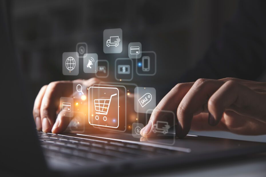 Young man using laptop with shopping cart icon.